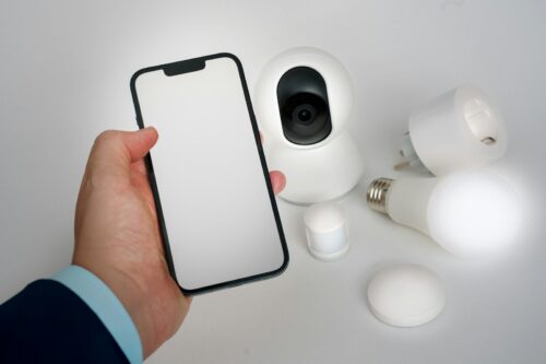 A person holding a smart phone next to a camera